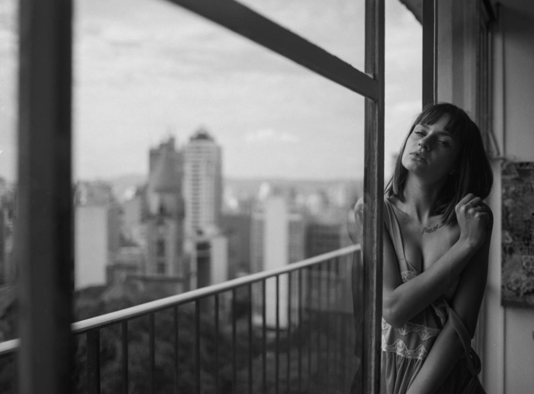 Modelo em pose sensual na varanda do apartamento com vista para os arranha céus