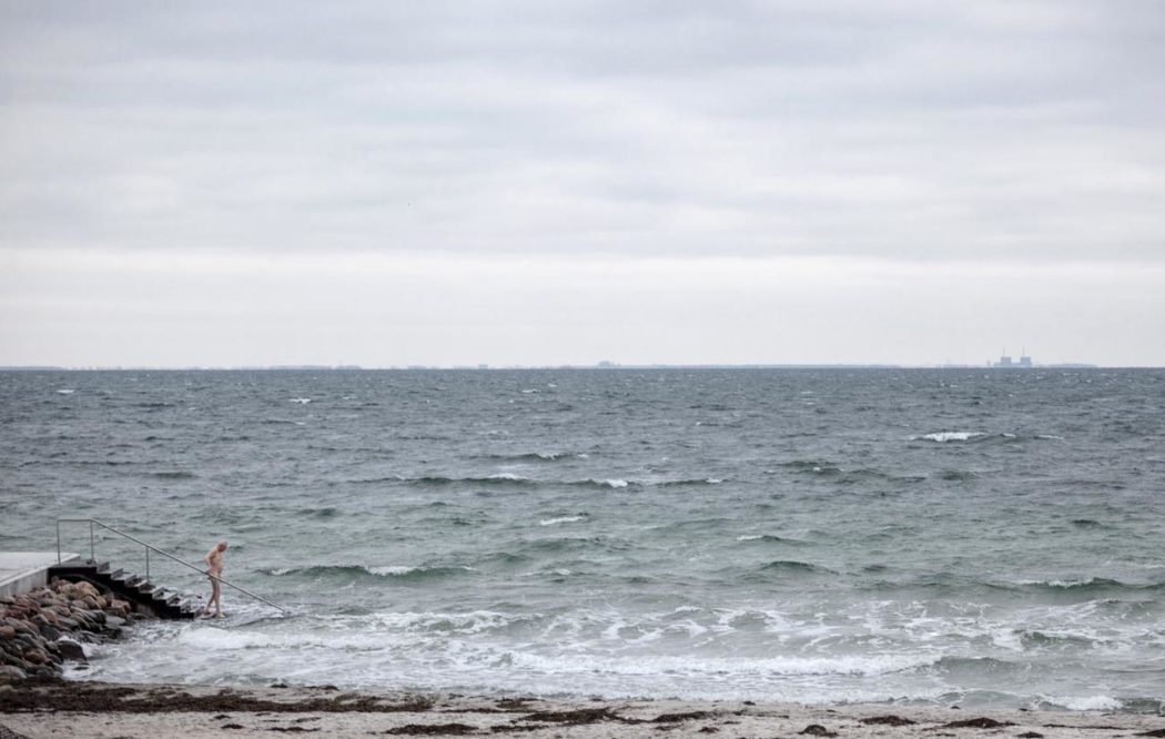 Homem idoso entrando no mar em Klampenborg durante o inverno