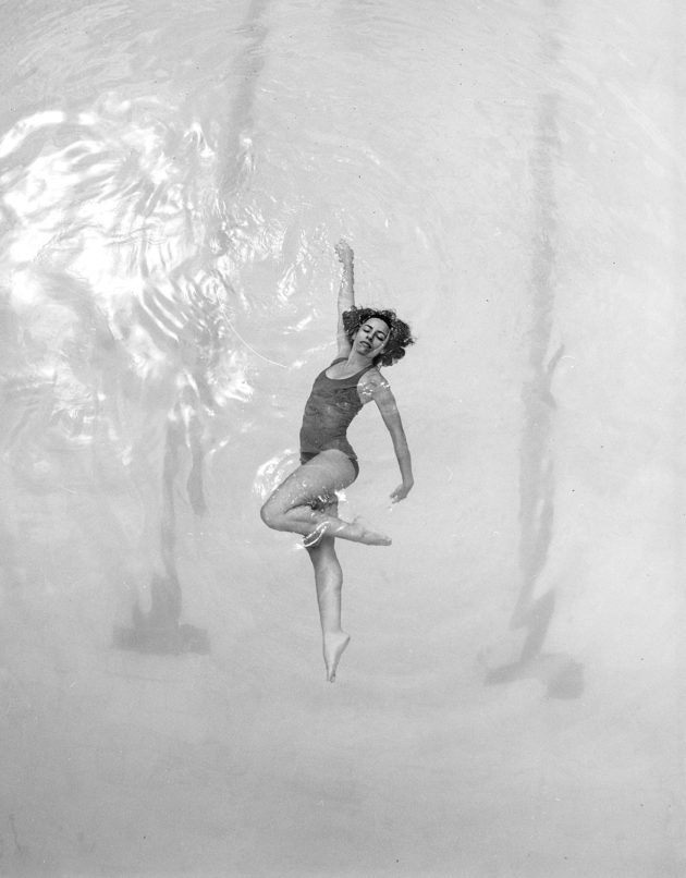 Modelo fotografada de cima em piscina olímpica nadando com body maiô
