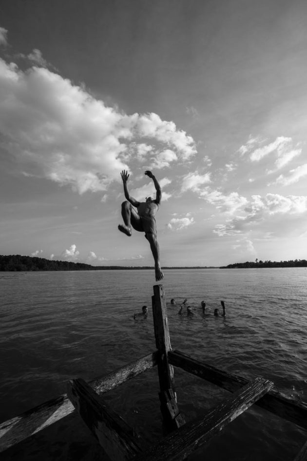 Menino saltando de deck para o Rio no Pará na Selva Amazônica