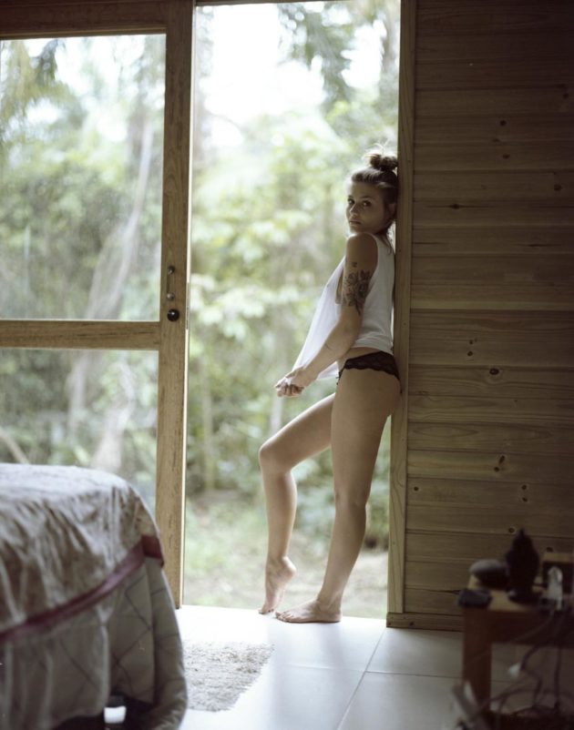 Modelo em pose sensual em porta de cabana madeira na praia