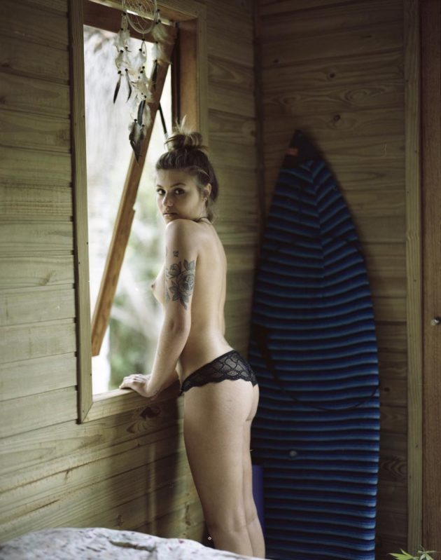 Modelo escorando sensualmente em janela sob luz suave do fim do dia em cabana de madeira