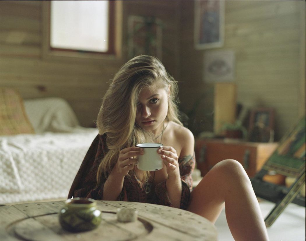 Retrato de garota segurando caneca de café pela manhã em cabana de madeira