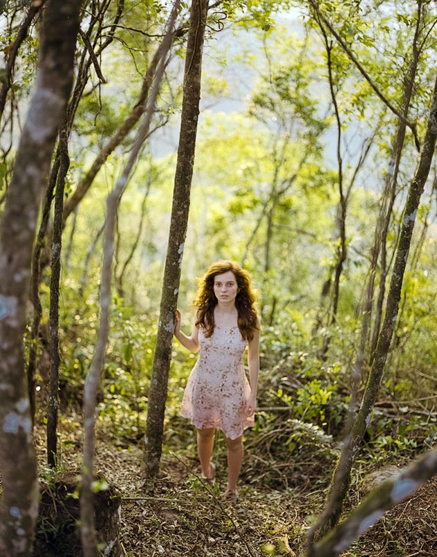 Retrato de garoa com expressão triste e bucólica na floresta verde com vestido rosa claro
