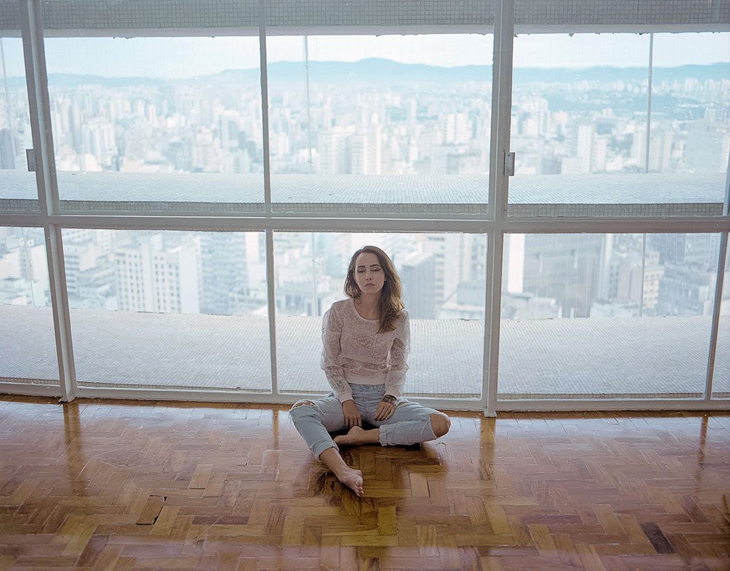 modelo sentada no apartamento do edifício Copan com vista para a cidade