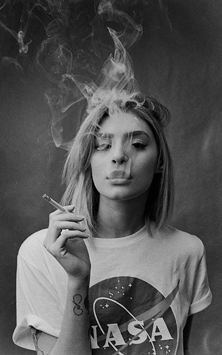 Modelo fumando em foto preto e branco com fumaça do cigarro