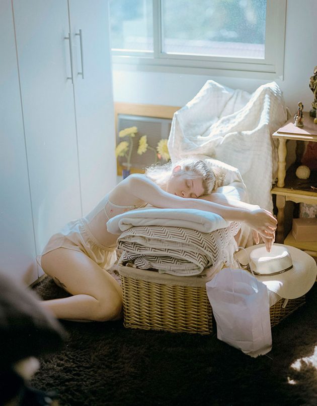 Modelo garota escorada sobre cobertores em luz suave e tons pasteis num apartamento