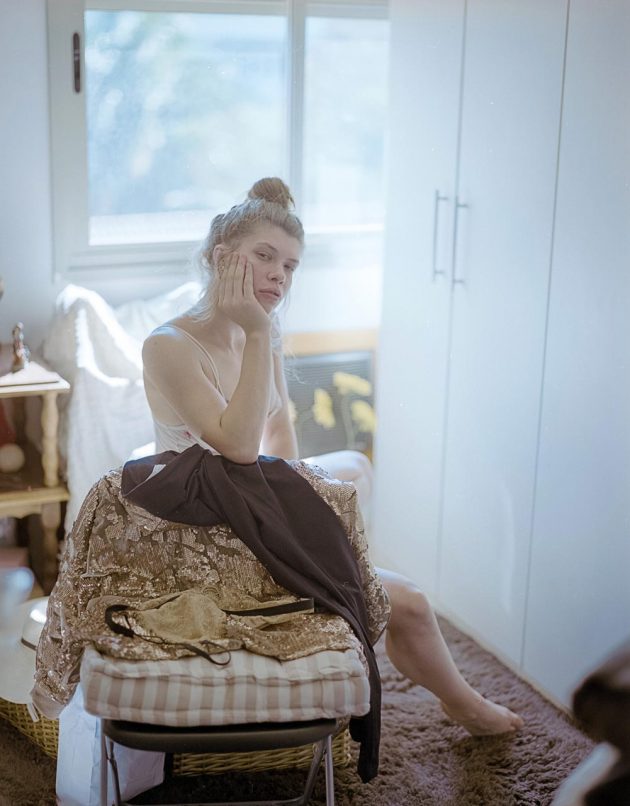Modelo garota sentada sobre cobertores em luz suave e tons pasteis num apartamento