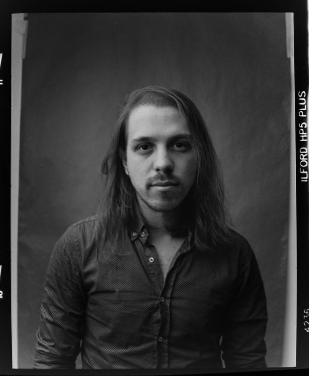 retrato de homem cabelo longo em estúdio foto preto e branco com fundo neutro