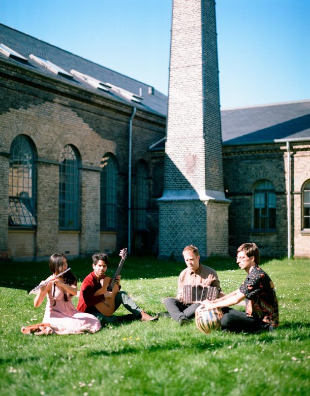 Banda musical de quatro integrantes sentados em gramado