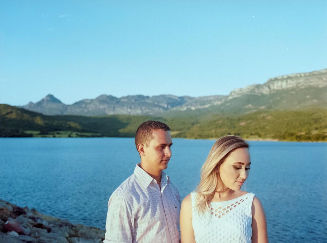 Ensaio de casal em pé com paisagem de montanhas ao fundo em Vila Serranópolis represa