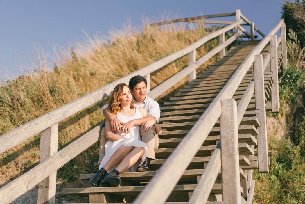Casal sentado em escada de madeira na praia
