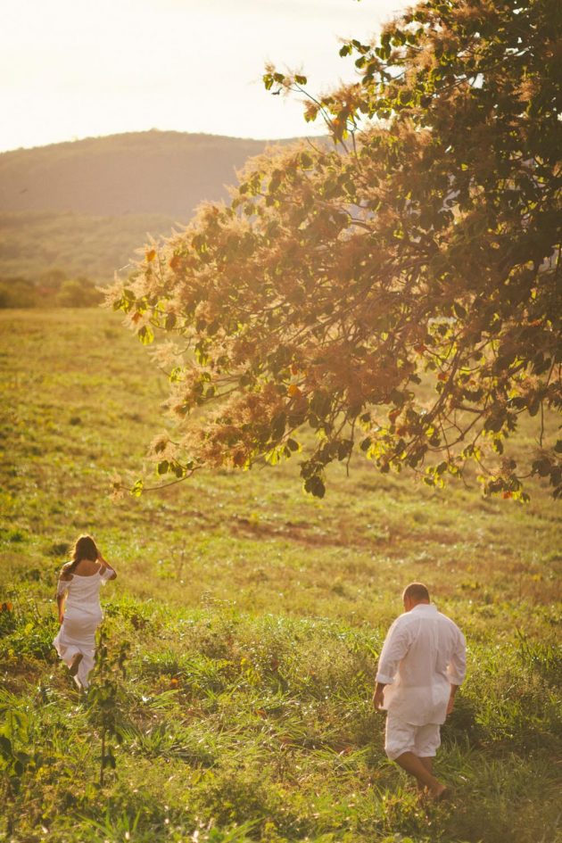 Ensaio de casal maduro meia idade em campo ensolarado com árvore roupas brancas