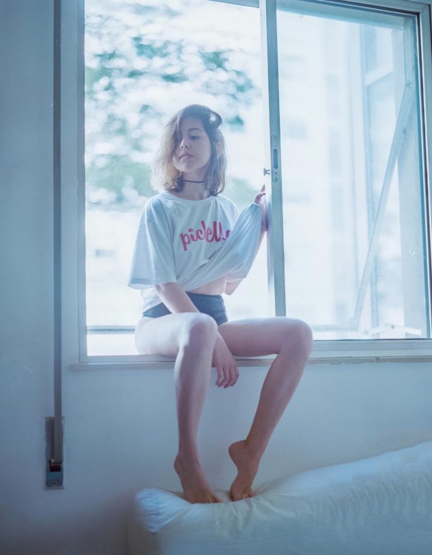 Garota branca do cabelo curto sentada na janela de lingerie e camiseta branca