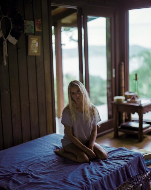 Garota menina loira sentada em casa de madeira com natureza ao fundo