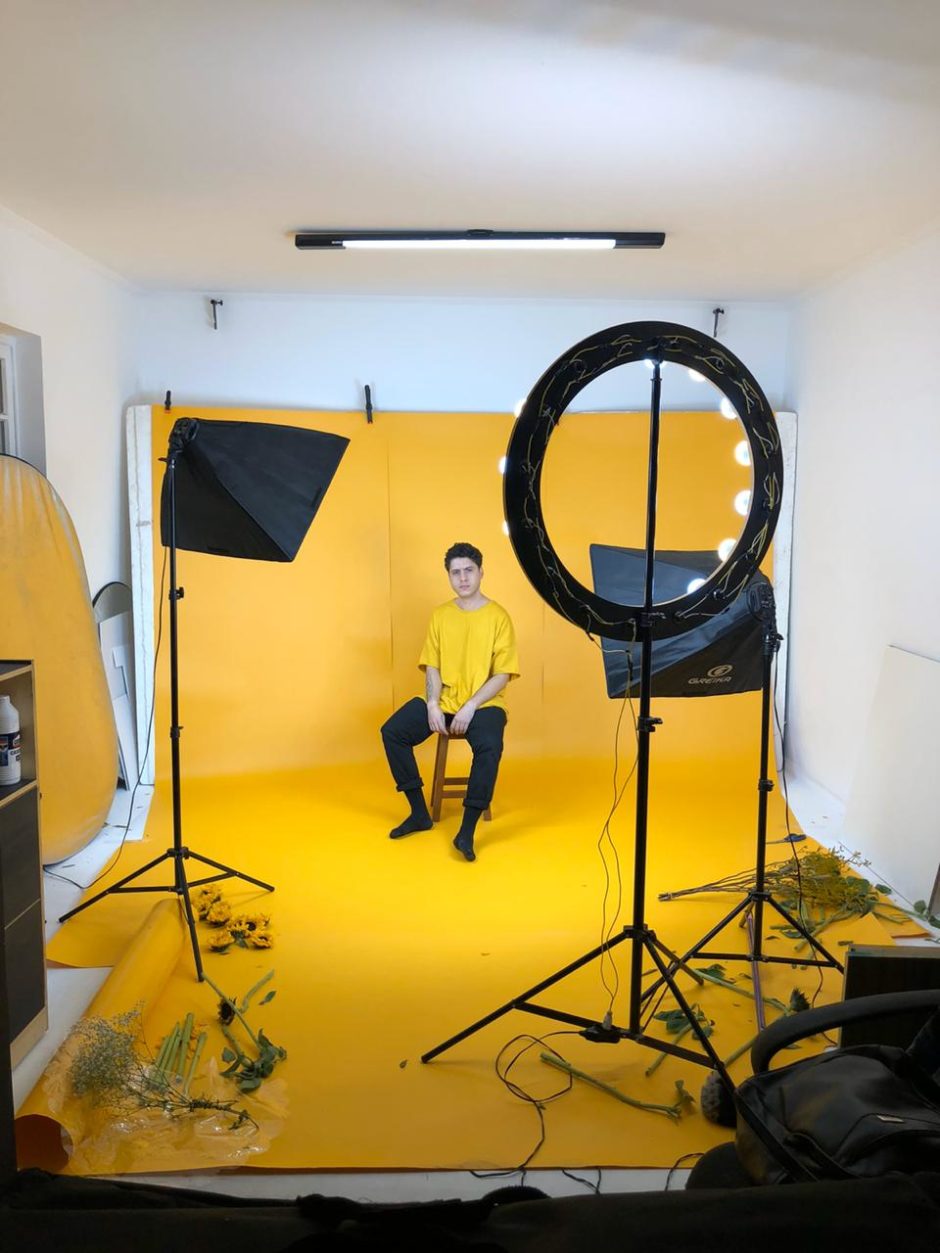 Thithi sentado em estúdio com fundo amarelo na gravação do clipe de jardim