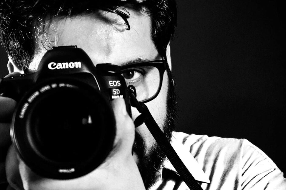 Homem em foto preto e branco com câmera em punho fotografando a si mesmo